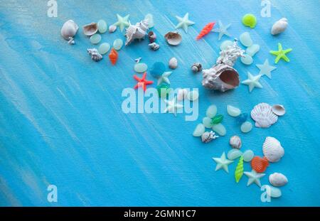 Seashells summer background. Many different seashells, starfish on a background of turquoise shimmering strokes. Creative flat lay banner, workspace c Stock Photo