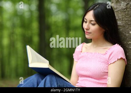 Asian woman reading paper book sitting in a park Stock Photo