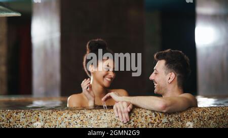 Portrait of happy young couple in love in swimming pool, having fun. Stock Photo