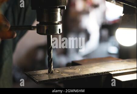 Worker hand working on milling machine to change metal drill bit. Tool for drilling metal workpiece. Milling machine. Steel manufacturing industry. Stock Photo