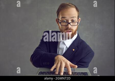 Young businessman in glasses developing his online business using laptop computer Stock Photo
