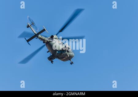 Dhruv, an advanced light helicopter developed by Hindustan Aeronautics Limited's, flies against the backdrop of a clear blue sky. Stock Photo