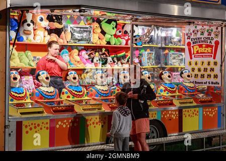 A 'laughing clowns' game at a nighttime carnival, with rows of stuffed toys to be won. Mount Maunganui, New Zealand Stock Photo