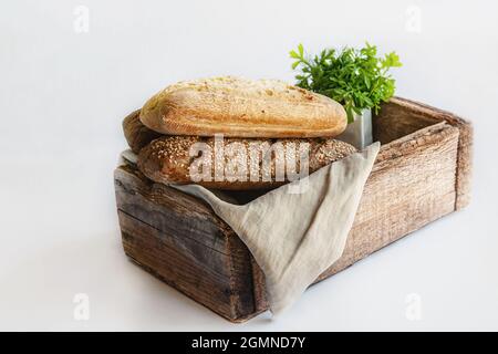 Assortment of bread in a wooden old rustic box. Various types of greens for bread. studio photo. Still-life. Stock Photo