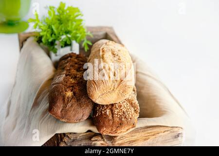 Assortment of bread in a wooden old rustic box. Various types of greens for bread. studio photo. Still-life. Stock Photo