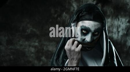 closeup of a scary evil nun, in a black and white habit, covering her ...