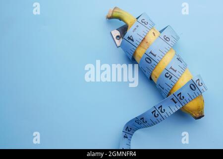 close up of measurement tape and banana on blue background  Stock Photo