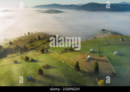 Mountain landscape with morning fog, at the forest edge, in the Romanian village Stock Photo