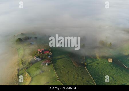 Mountain landscape with morning fog, at the forest edge, in the Romanian village Stock Photo