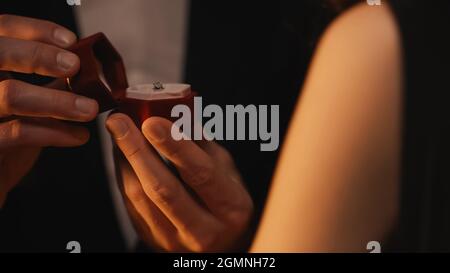cropped view of man holding red box while making proposal to blurred woman Stock Photo