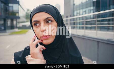 Arabian woman in hijab having phone call outside Stock Photo