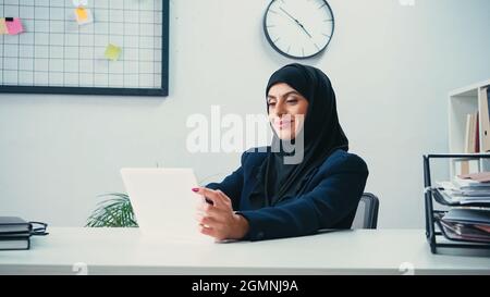 Smiling muslim businesswoman using digital tablet in office Stock Photo