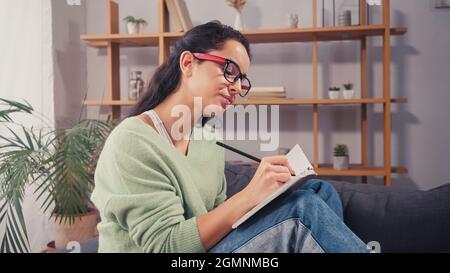 Brunette student writing on notebook at home Stock Photo