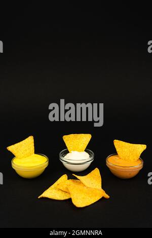 Fast food. Nachos chips with different sauces on a black background with place for text vertical photo. Stock Photo