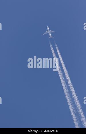 Twin engined Aeroplane in the clear blue sky leaving vapor trails behind Stock Photo