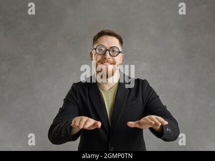 Studio portrait of funny nerd in round frame glasses dancing and looking at camera Stock Photo