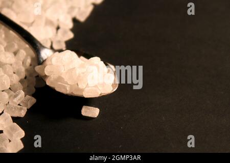Big sugar crystals with spoon on black background Stock Photo