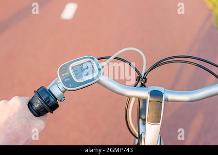 First person perspective on Control Panel on Handlebar of Electric Bicycle while driving on Bicycle lane Stock Photo