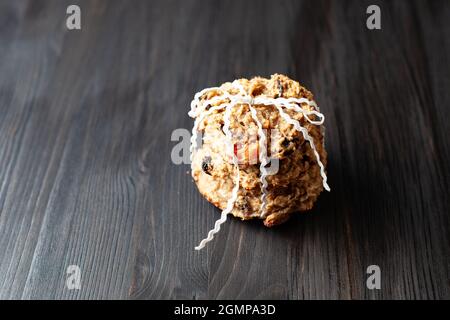 Homemade oatmeal raisin cookies, tied with white braid on a black wooden background Stock Photo