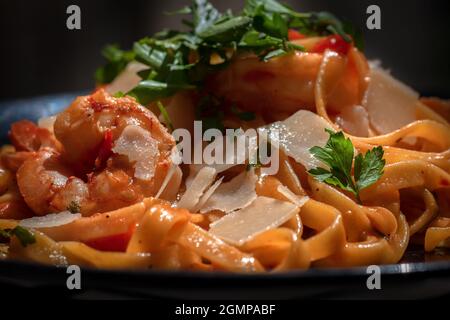Shrimp scampi a classic in Italian cuisine. Shrimp and linguine in a lemon, butter, garlic BBQ sauce. Linguine with tomatoes, greens, and shrimp. Stock Photo