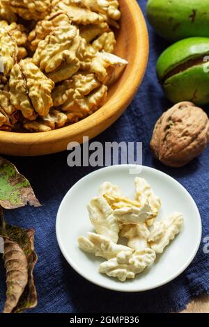 Young walnuts, shelled and in shell, walnut leaves. Rustic style. Stock Photo