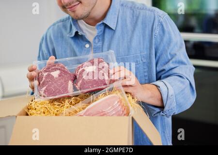 Man Unpacking Online Luxury Meat Order Of Steak And Bacon Delivered To Home Stock Photo