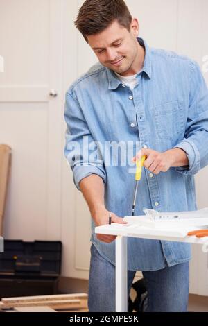 Man Putting Together Self Assembly Furniture At Home Stock Photo