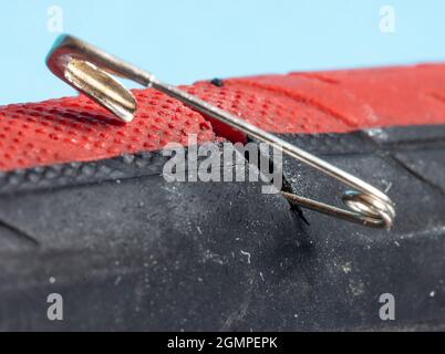 The bicycle tire is damaged by a safety pin, close up view.