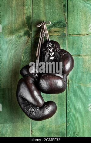 old boxing gloves hanging in front of rustic wooden wall Stock Photo
