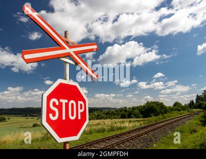 A red STOP sign before crossing the tracks. Stock Photo