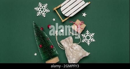 New Year and Christmas composition from decorative chrismas tree, sledge, snowflakes on green paper background. Stock Photo