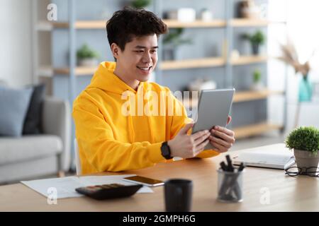 Smiling asian man using digital tablet at home Stock Photo