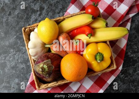 Basket with vegetables and fruits on kitchen towel on black smokey table Stock Photo