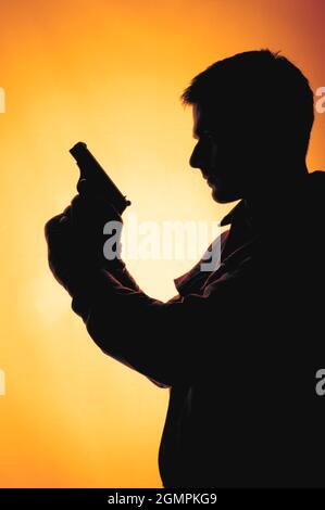 Silhouette of a man holding a gun Stock Photo - Alamy