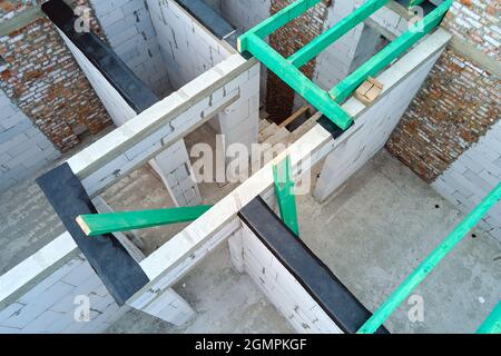 Aerial view of unfinished frame of private house with aerated lightweight concrete walls and wooden roof beams under construction. Stock Photo