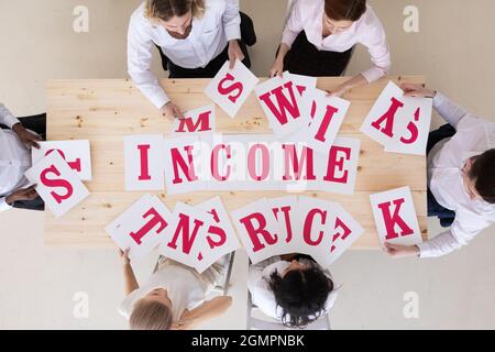 Multi-ethnic group of diverse business people putting letters INCOME finance teamwork cooperation concept Stock Photo