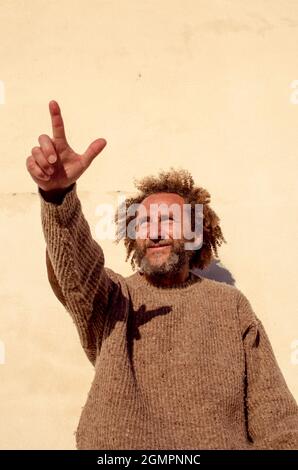 middle-aged man with curly hair raising his arm and pointing his finger Stock Photo