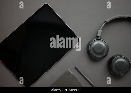 headphones and tablet with pencil and notebook on total black background. workflow start. Top view Stock Photo