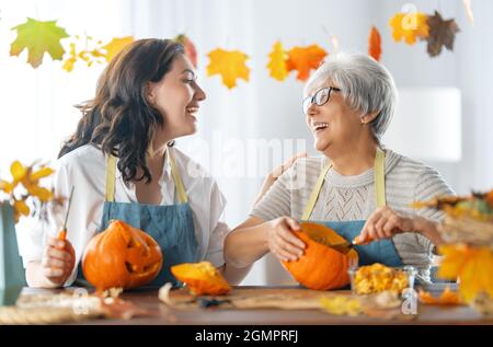 Happy Halloween! Mother and her adult daughter carving pumpkin. Family preparing for holiday. Stock Photo