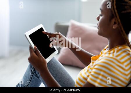 Side view of black woman using pad with empty screen Stock Photo