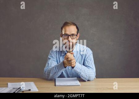 Serious confident job candidate or HR manager sitting at desk during job interview Stock Photo