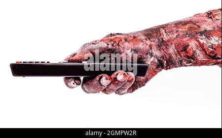 zombie hand holding a television remote control, isolated white background, halloween theme. Stock Photo