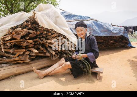 Sapa, Vietnam - April 14, 2016: Old vietnamese woman in the village near Sapa doing handmade thread of hemp. Black Hmong minority women in traditional Stock Photo