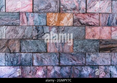 Decorative wall cladding with multi-colored granite tiles. Background from colored natural stones. Decorative cladding with multi-colored natural ston Stock Photo