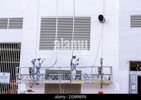 Miami Florida,Paramount Bay,under new construction site building men painters painting workers,swing stage elevated work platform suspension lines Stock Photo