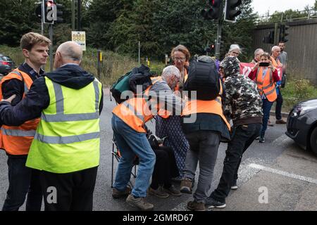 Godstone, UK. 13th September, 2021. A man tries to pull away a banner from Insulate Britain climate activists blocking a slip road from the M25, causing a long tailback on the motorway, as part of a new campaign intended to push the UK government to make significant legislative change to start lowering emissions. The activists, who wrote to Prime Minister Boris Johnson on 13th August, are demanding that the government immediately promises both to fully fund and ensure the insulation of all social housing in Britain by 2025 and to produce within four months a legally binding national plan to fu Stock Photo