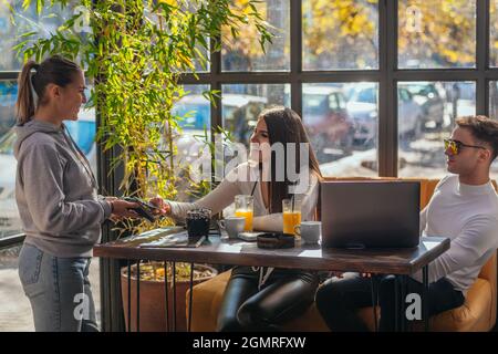Side view of a couple paying bill at coffee shop using credit card payment Stock Photo