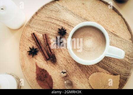 A cup of coffee with star anise, nutmeg and cinnamon sticks on a wooden tray. Autumn flat lay, hot drink, cozy home. Top view Stock Photo