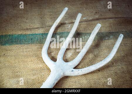 Old white deformed pitchfork isolated on a textile background Stock Photo