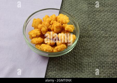 Sweet and spicy rice cracker balls in glass snack bowl with lavender napkin Stock Photo